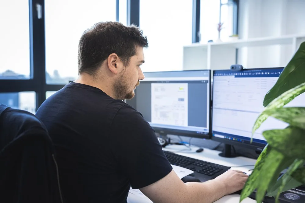 Mitarbeiter arbeitet an zwei Bildschirmen im Büro